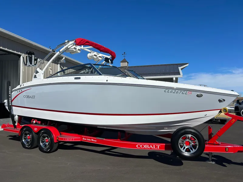 Slide: The Image of 2020 Cobalt R5 Surf boat on red trailer, parked outdoors under clear blue sky. - 4