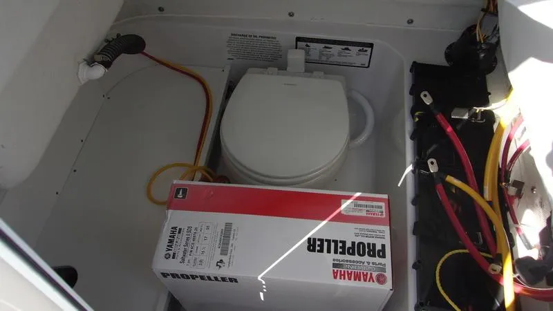 Slide: The Image of Boat storage compartment with Yamaha propeller box and portable toilet, Sportsman Open 232, 2025 model. - 12