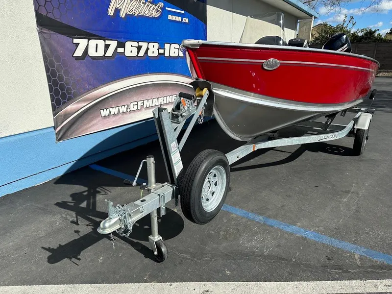 Slide: The Image of 2025 Lund 1400 Fury SS boat on trailer, red and silver, parked outdoors. - 3