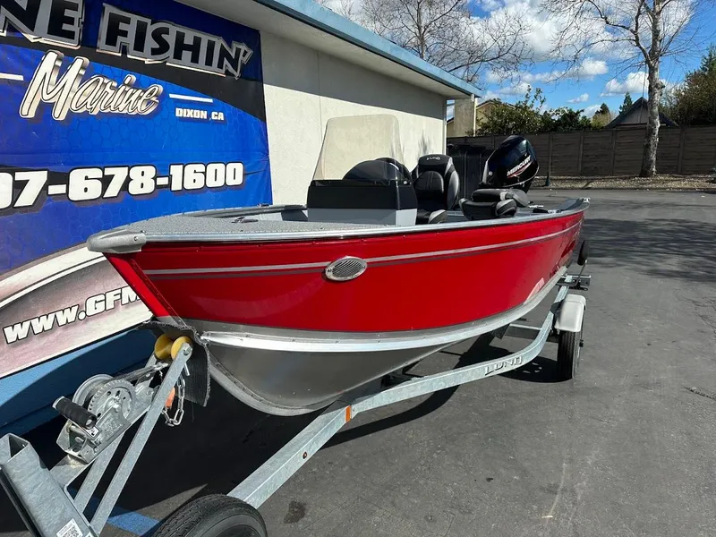 Slide: The Image of 2025 Lund 1400 Fury SS boat in red on a trailer, parked outside a marine shop. - 4