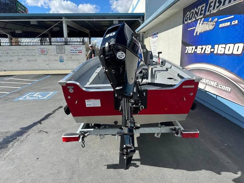 Slide: The Image of 2025 Lund 1400 Fury SS boat with outboard motor, parked outdoors. - 7
