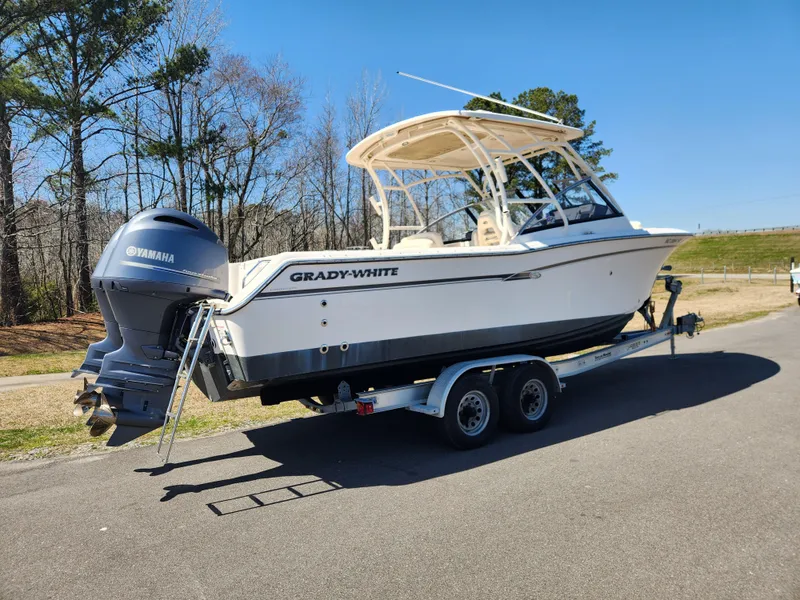 Slide: The Image of 2015 Grady-White Freedom 275 boat on trailer, parked on road, clear sky background. - 2