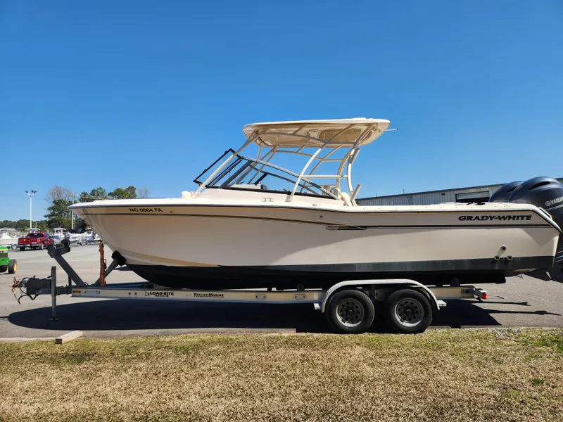 Slide: The Image of 2015 Grady-White Freedom 275 boat on trailer, parked outdoors under clear blue sky. - 6