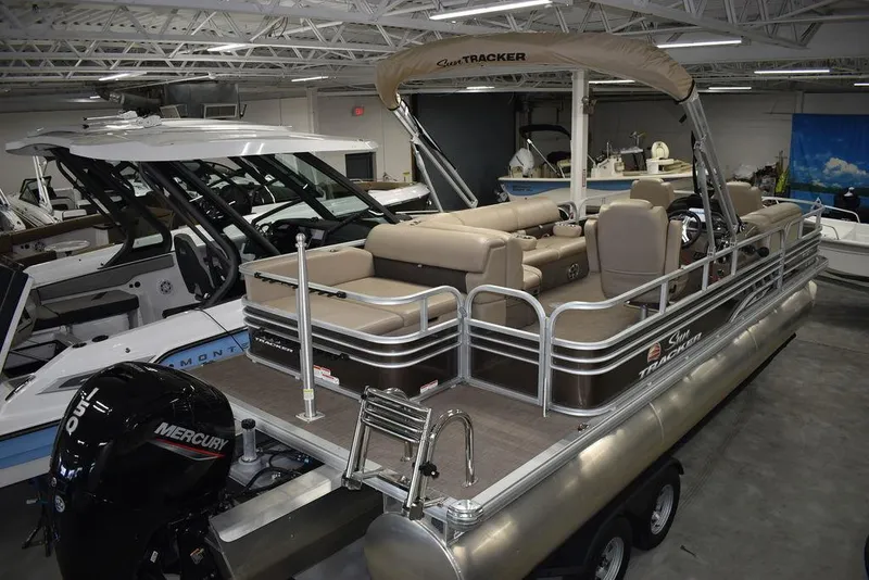 Slide: The Image of 2023 Sun Tracker Sportfish™ 24 XP3 pontoon boat in showroom, featuring Mercury outboard motor. - 10