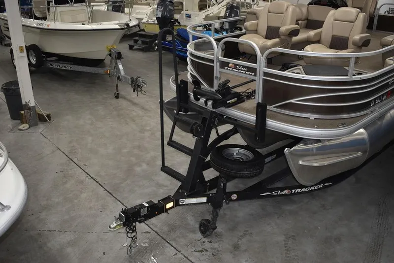 Slide: The Image of 2023 Sun Tracker Sportfish™ 24 XP3 pontoon boat in showroom, featuring trailer and seating. - 7