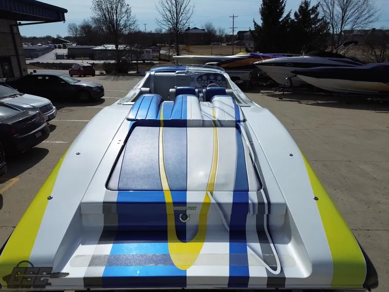 Slide: The Image of 2007 Outerlimits 39 Quattro speedboat with vibrant blue, yellow, and white design in a parking area. - 30