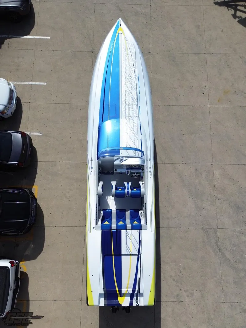 Slide: The Image of 2007 Outerlimits 39 Quattro speedboat with vibrant blue and yellow design, parked on concrete. - 40