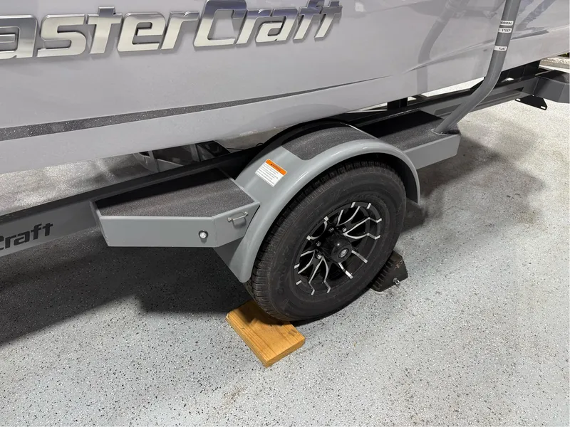 Slide: The Image of 2025 MasterCraft ProStar trailer with black wheel, parked on concrete floor. - 10