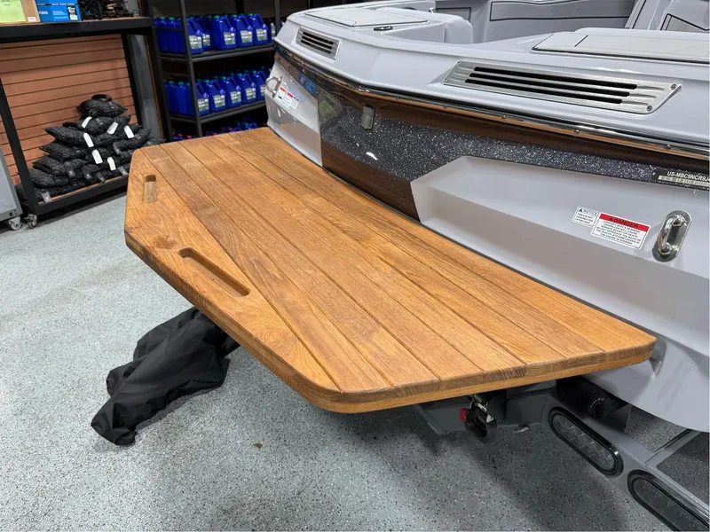 Slide: The Image of 2025 MasterCraft ProStar boat with wooden swim platform in a showroom. - 13