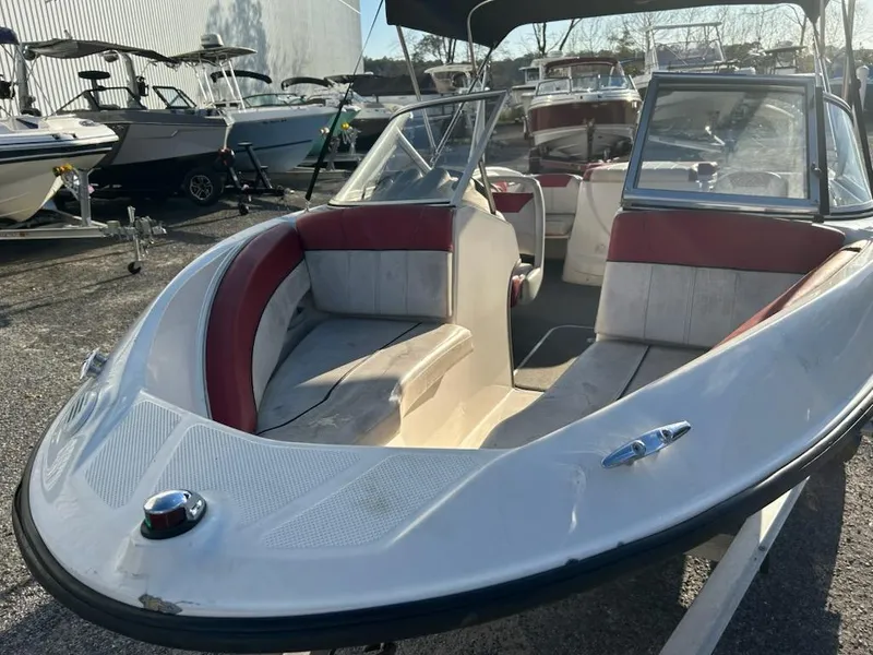 Slide: The Image of 2012 Bayliner 185 Bowrider boat with red and white seating, parked outdoors. - 4