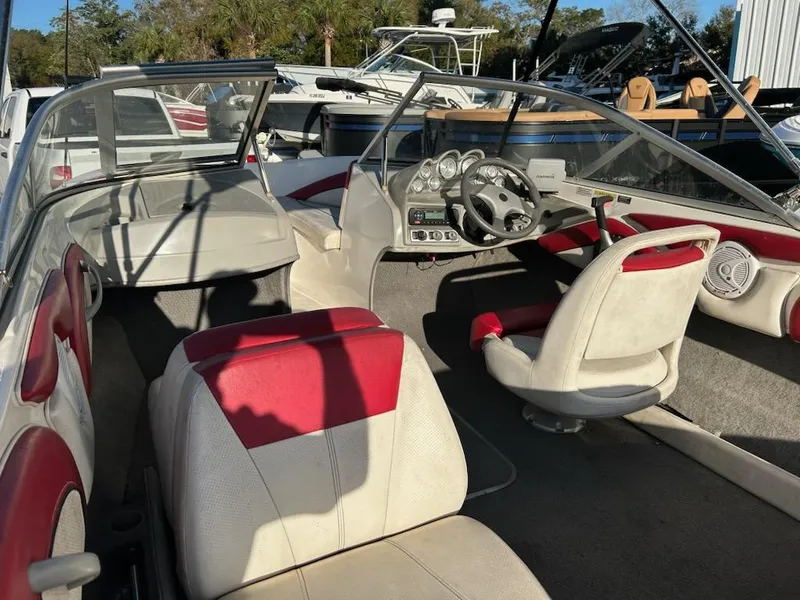 Slide: The Image of 2012 Bayliner 185 Bowrider interior with red and white seating, steering wheel, and dashboard. - 5