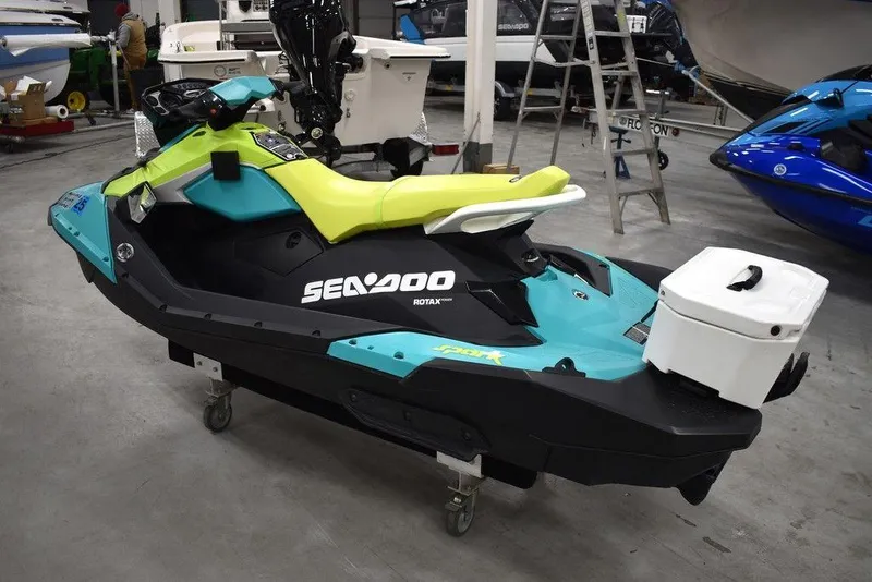 Slide: The Image of 2022 Sea-Doo Spark 3-up Rotax 900 ACE with Audio, teal and yellow, in showroom. - 3