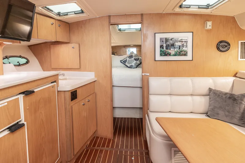 Slide: The Image of 1998 Tiara Yachts 3500 Open interior with wood cabinetry, white seating, and cozy dining area. - 2