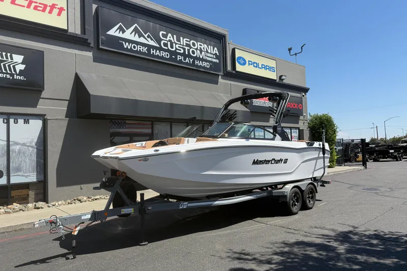 The Image of 2025 MasterCraft XT24 boat on trailer outside California Custom store. - 0
