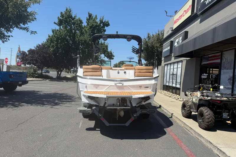 Slide: The Image of 2025 MasterCraft XT24 boat parked outside dealership, rear view with tan seating. - 6