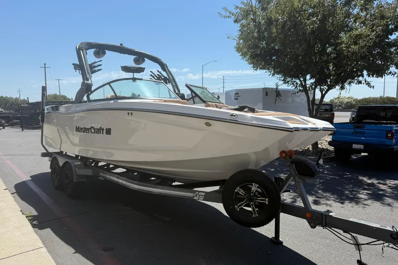 Slide: The Image of 2025 MasterCraft XT24 boat on trailer in parking lot, sunny day. - 8