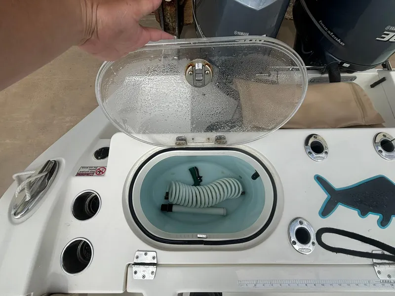 Slide: The Image of 2017 Cobia 296 Center Console boat with open storage compartment and hose. - 18