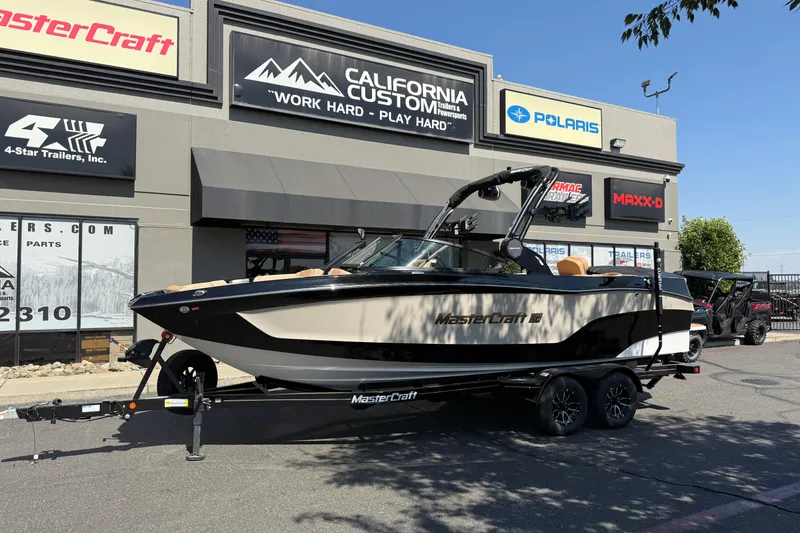 The Image of 2025 MasterCraft XT24 boat on trailer outside dealership, showcasing sleek design and modern features. - 0