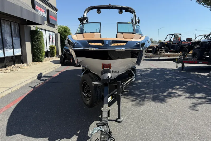 Slide: The Image of 2025 MasterCraft XT24 boat on trailer, parked outdoors near dealership. - 10