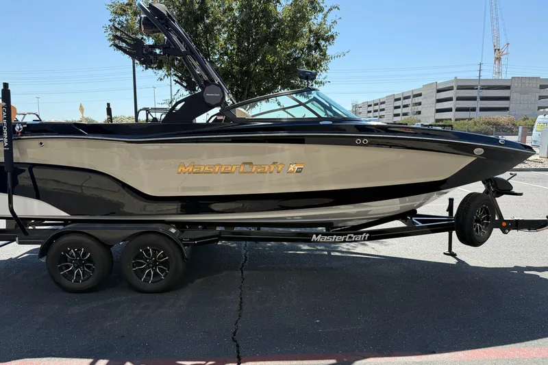 Slide: The Image of 2025 MasterCraft XT24 boat on trailer, parked outdoors, showcasing sleek design and branding. - 8
