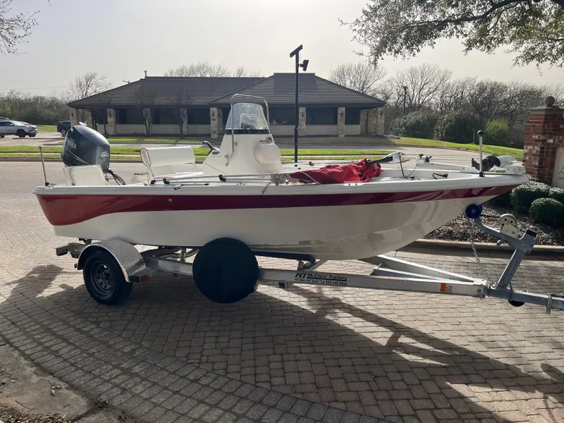 Slide: The Image of 2012 NauticStar 1810 boat on trailer, parked outdoors, featuring a red and white design. - 13