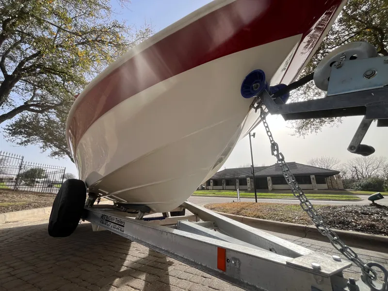 Slide: The Image of 2012 NauticStar 1810 boat on trailer, parked outdoors under trees. - 15