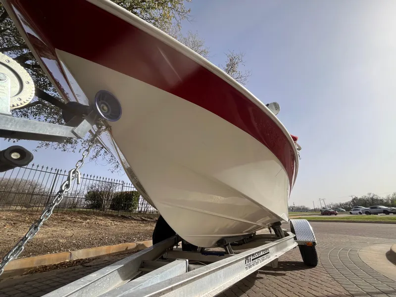 Slide: The Image of 2012 NauticStar 1810 boat on trailer, red and white hull, parked outdoors. - 16