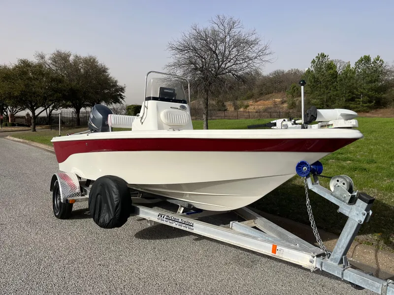 Slide: The Image of 2012 NauticStar 1810 boat on trailer, parked on roadside with trees in background. - 29