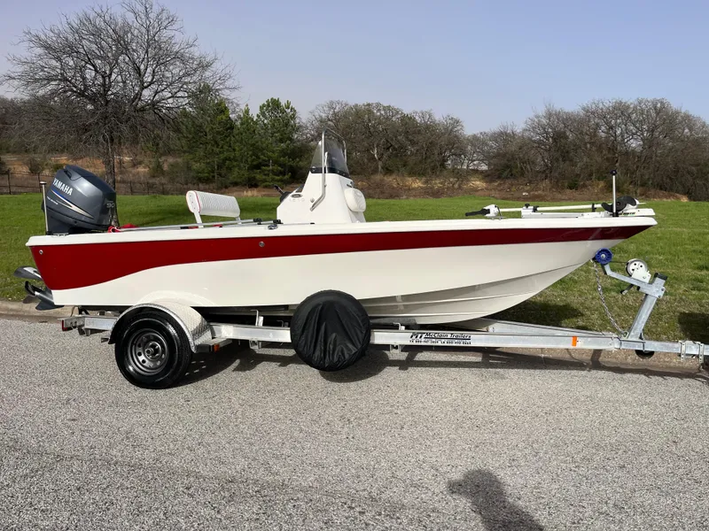 Slide: The Image of 2012 NauticStar 1810 boat on trailer, red and white design, parked on roadside. - 30
