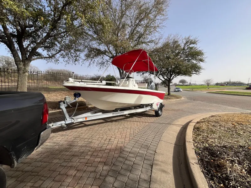 Slide: The Image of 2012 NauticStar 1810 boat with red canopy on trailer, parked on brick road. - 33
