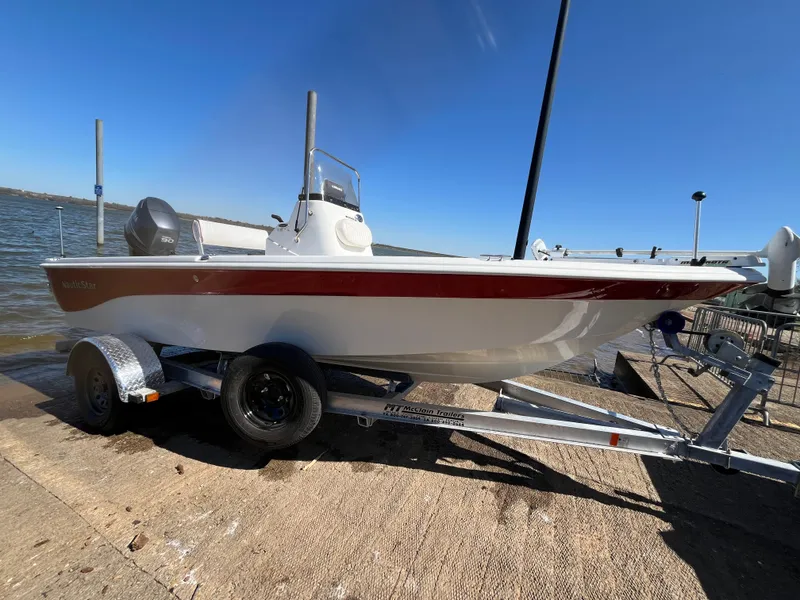 Slide: The Image of 2012 NauticStar 1810 boat on trailer by the water, clear sky background. - 36