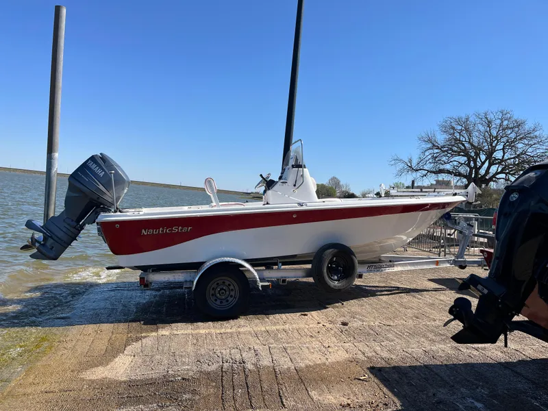 Slide: The Image of 2012 NauticStar 1810 boat on trailer by lake, clear sky background. - 37