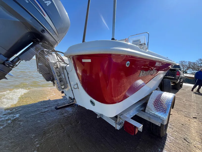 Slide: The Image of 2012 NauticStar 1810 boat with red hull on trailer by water. - 38