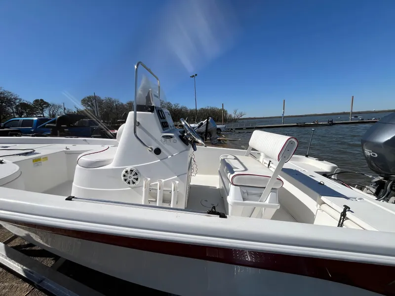 Slide: The Image of 2012 NauticStar 1810 boat with white interior, docked by a lake under clear blue sky. - 44