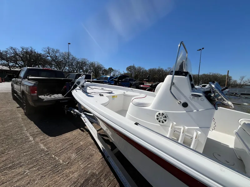 Slide: The Image of 2012 NauticStar 1810 boat on trailer, parked beside a truck under clear blue sky. - 45