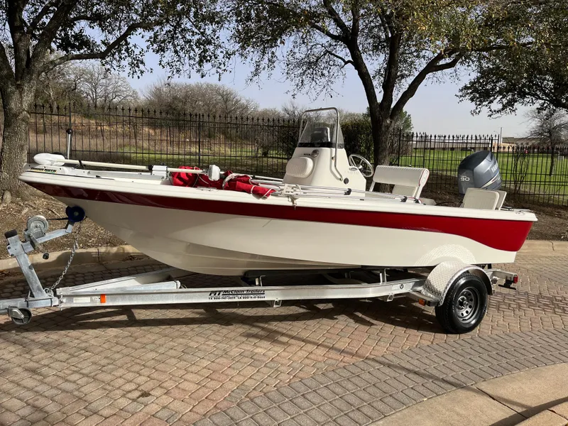 Slide: The Image of 2012 NauticStar 1810 boat on trailer, red and white design, parked outdoors. - 5