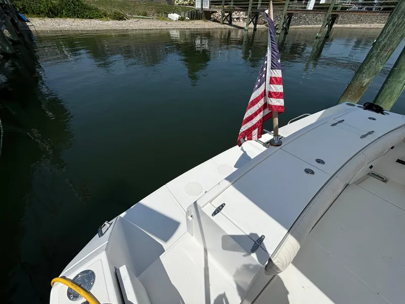Slide: The Image of 2005 Stamas 310 Tarpon boat docked, featuring an American flag and clean white deck. - 13