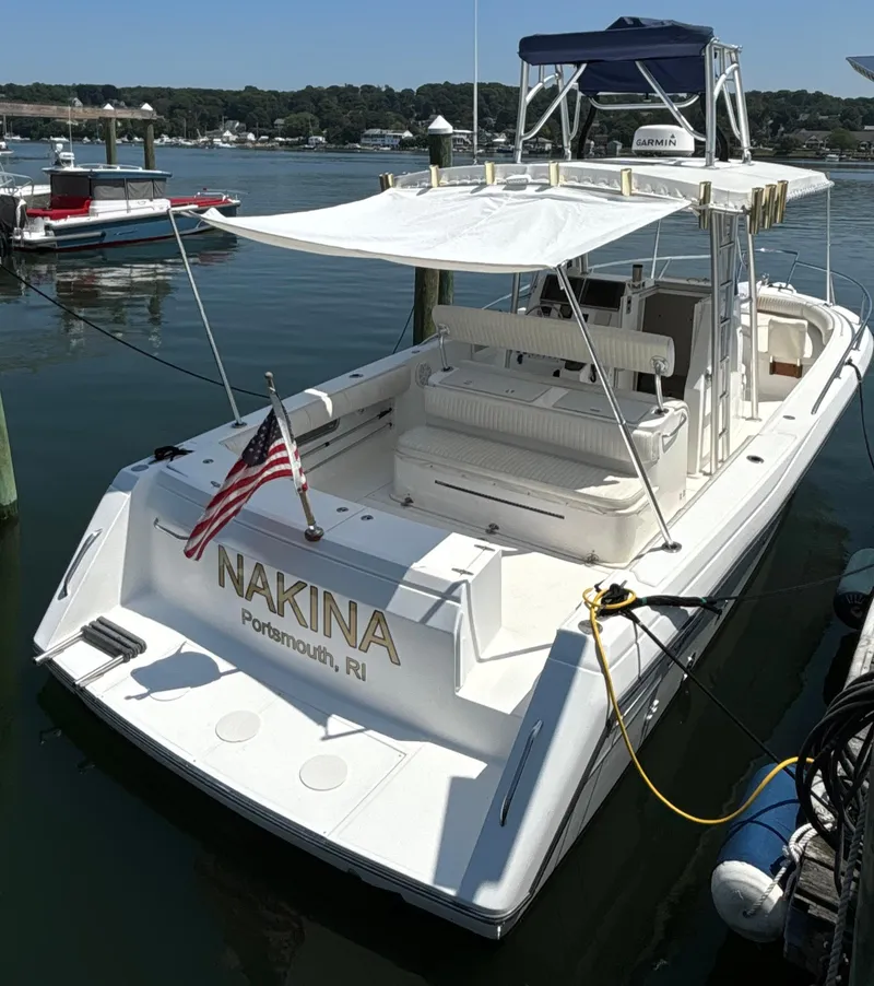 Slide: The Image of 2005 Stamas 310 Tarpon boat docked, featuring a canopy and American flag. - 3