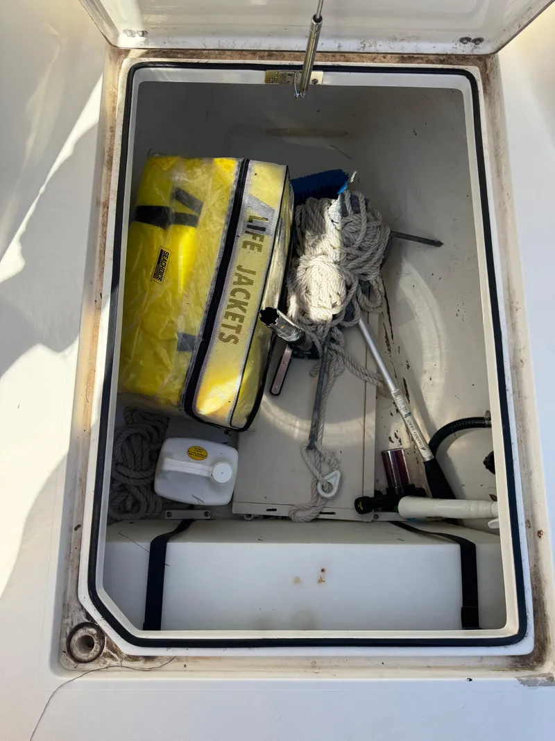 Slide: The Image of Storage compartment on a 2013 Cobia 296 Center Console boat with safety gear and ropes. - 15