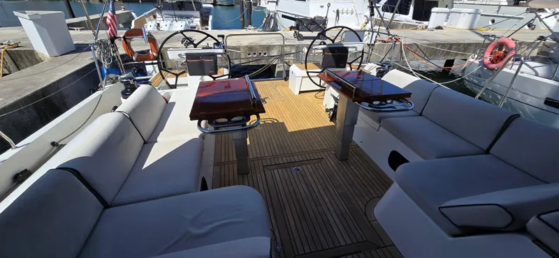 Slide: The Image of 2021 Beneteau Oceanis Yacht 54 cockpit with dual steering wheels and cushioned seating. - 13