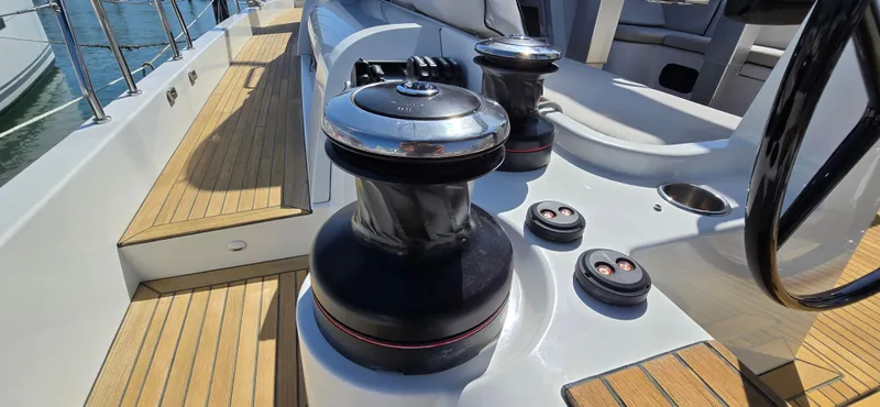 Slide: The Image of 2021 Beneteau Oceanis Yacht 54 deck with winches and steering wheel, showcasing teak flooring. - 17