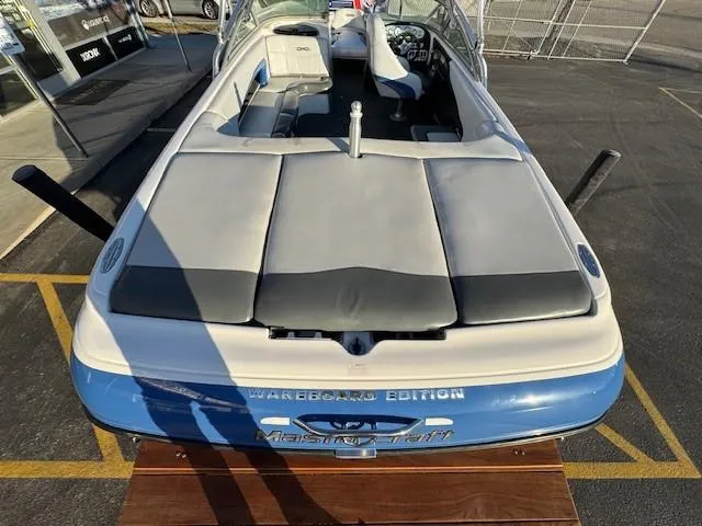 Slide: The Image of 2004 MasterCraft X-30 wakeboard boat, rear view, blue and white design, parked outdoors. - 10