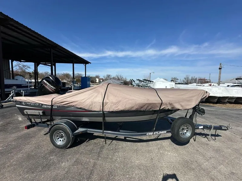 Slide: The Image of 2013 Crestliner Fish Hawk 1750 boat covered on trailer, parked outdoors. - 14