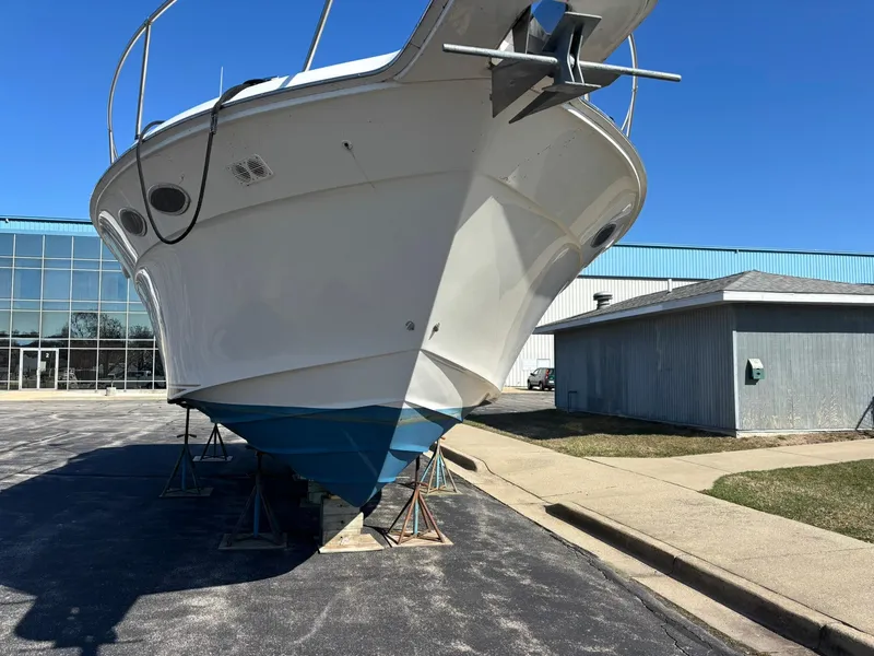 Slide: The Image of 1999 Sea Ray 370 Express Cruiser on stands, outside a building, under clear blue sky. - 1