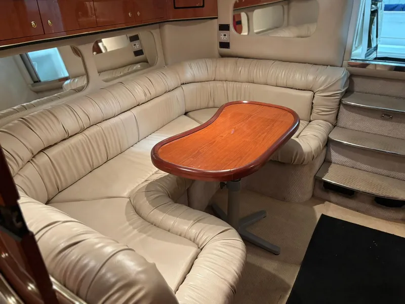 Slide: The Image of 1999 Sea Ray 370 Express Cruiser interior with beige leather seating and wooden table. - 32