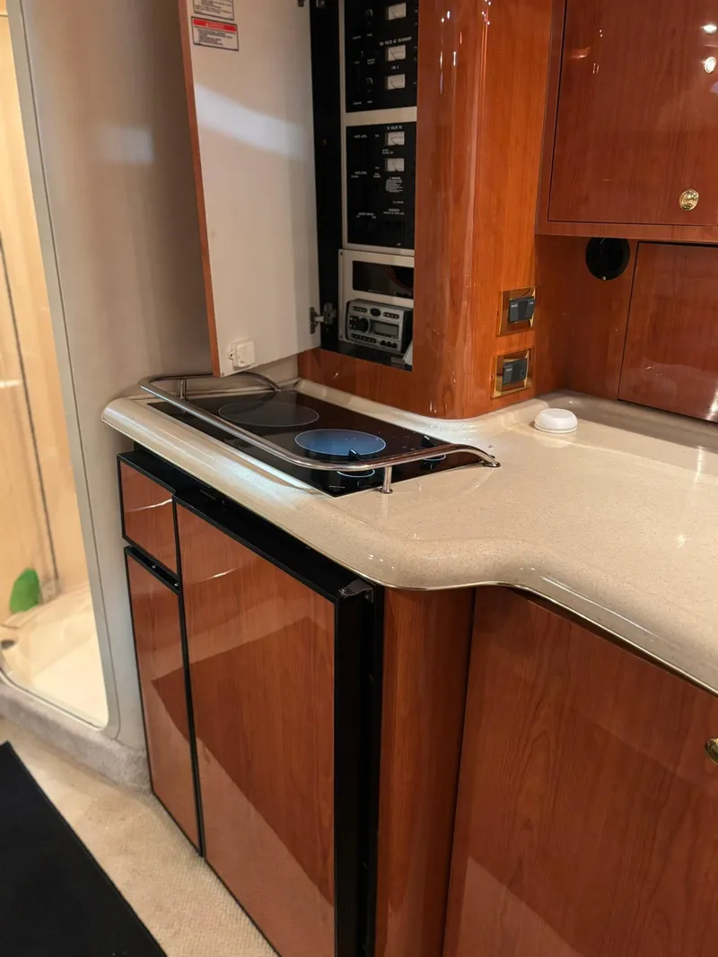 Slide: The Image of 1999 Sea Ray 370 Express Cruiser kitchen with stove, fridge, and wood cabinetry. - 33