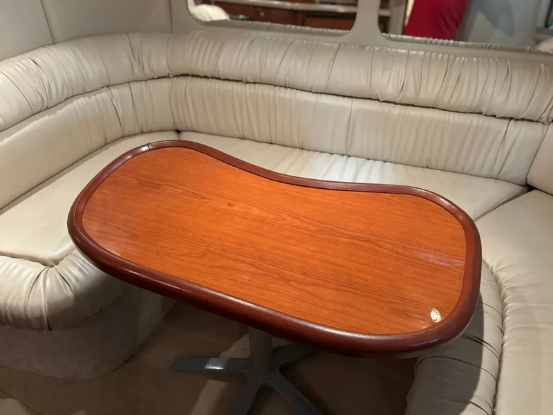 Slide: The Image of Interior of 1999 Sea Ray 370 Express Cruiser with wooden table and leather seating. - 42