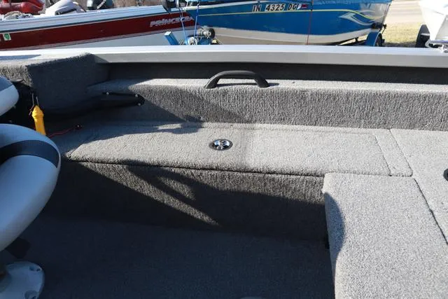 Slide: The Image of 2013 Alumacraft Navigator 165 CS boat interior with gray carpeted seating and storage. - 11