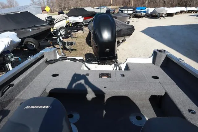 Slide: The Image of 2013 Alumacraft Navigator 165 CS boat interior with motor, parked among covered boats. - 6