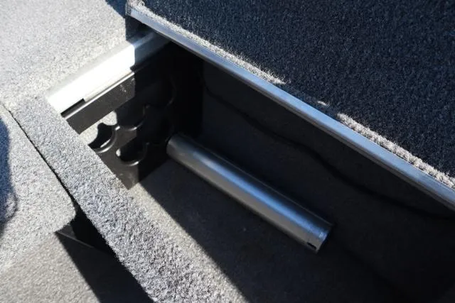 Slide: The Image of 2013 Alumacraft Navigator 165 CS storage compartment with rod holder and carpeted interior. - 9